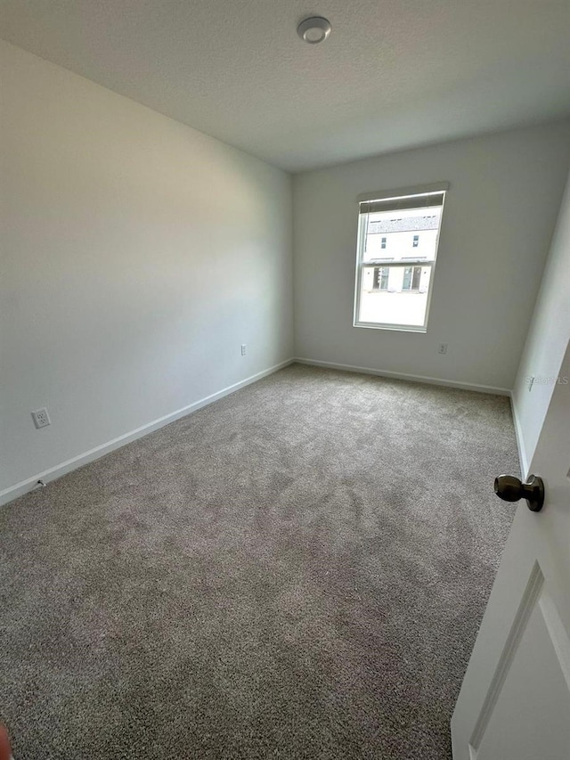 spare room featuring carpet floors and baseboards