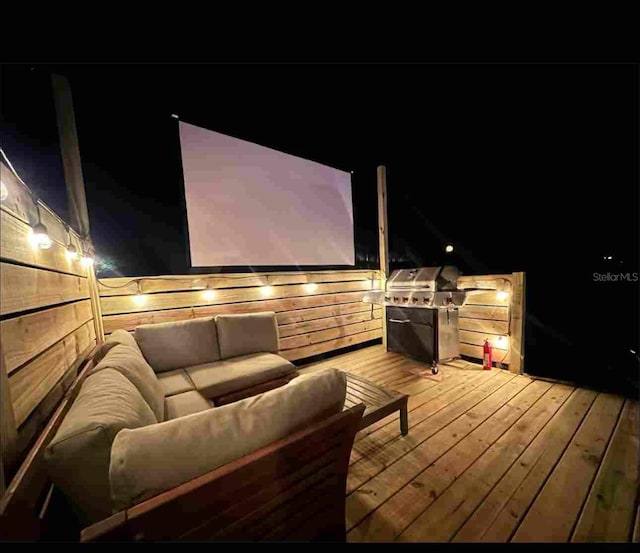 deck at twilight with an outdoor living space and grilling area
