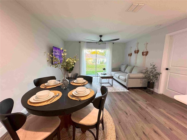 dining room with wood finished floors, a ceiling fan, and baseboards