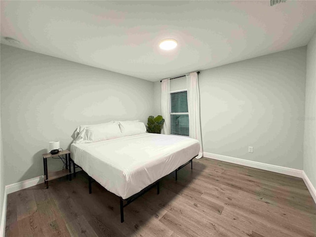 bedroom with baseboards and wood finished floors