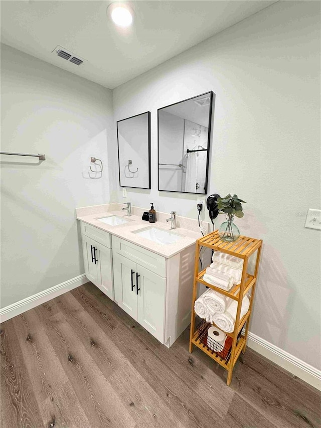 full bathroom featuring wood finished floors, baseboards, and double vanity