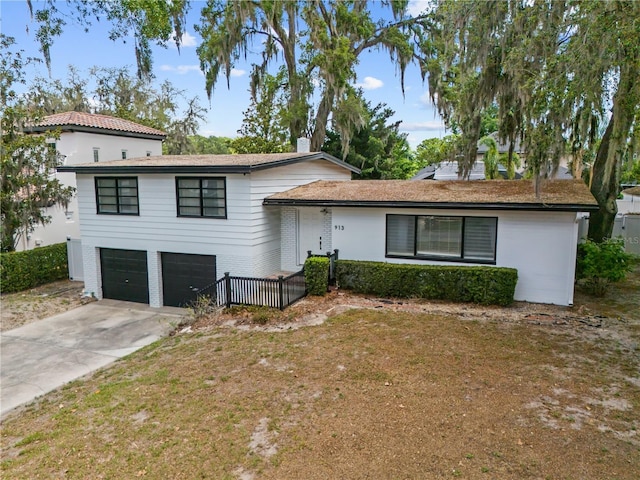 913 Moss Ln, Winter Park, FL 32789 - tri-level home featuring a garage, concrete driveway, and brick siding