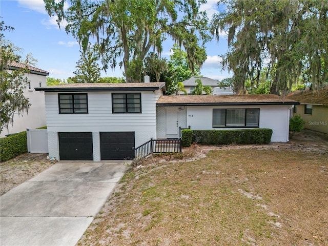 913 Moss Ln, Winter Park, FL 32789 - view of front of property featuring an attached garage, concrete driveway, brick siding, a front yard, and a chimney