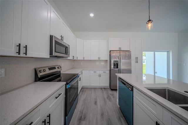 kitchen with stainless steel appliances, white cabinets, light stone countertops, light wood-style flooring, and hanging light fixtures