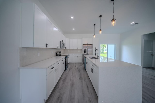 kitchen featuring stainless steel appliances, a sink, light wood finished floors, decorative backsplash, and recessed lighting