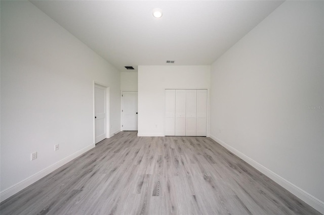 unfurnished bedroom with light wood finished floors, a closet, and baseboards