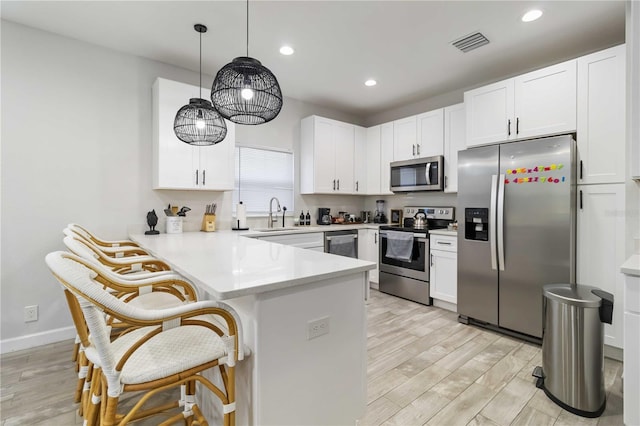 18 S D St, Lake Worth, FL 33460 - kitchen with appliances with stainless steel finishes, a peninsula, a breakfast bar area, white cabinetry, and recessed lighting
