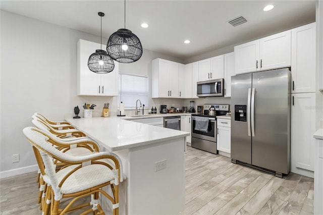 18 S D St, Lake Worth, FL 33460 - kitchen with appliances with stainless steel finishes, a peninsula, a breakfast bar area, white cabinets, and recessed lighting