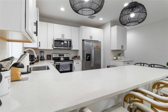 18 S D St, Lake Worth, FL 33460 - kitchen featuring stainless steel appliances, a sink, a kitchen bar, white cabinets, and a peninsula