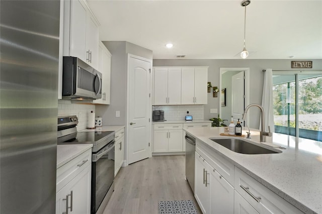 kitchen featuring stainless steel appliances, a sink, white cabinetry, and recessed lighting