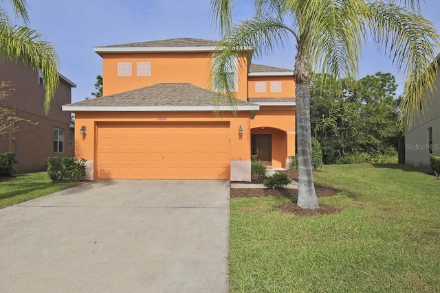 traditional-style house with stucco siding, a front yard, concrete driveway, and an attached garage