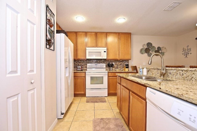 kitchen featuring white appliances, a sink, brown cabinets, and tasteful backsplash
