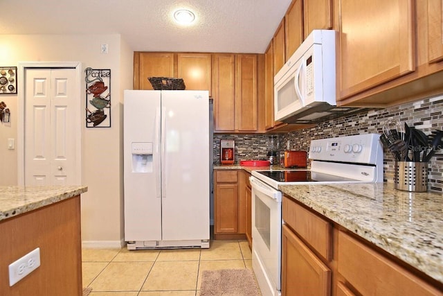 kitchen featuring white appliances, tasteful backsplash, light tile patterned floors, brown cabinets, and a textured ceiling