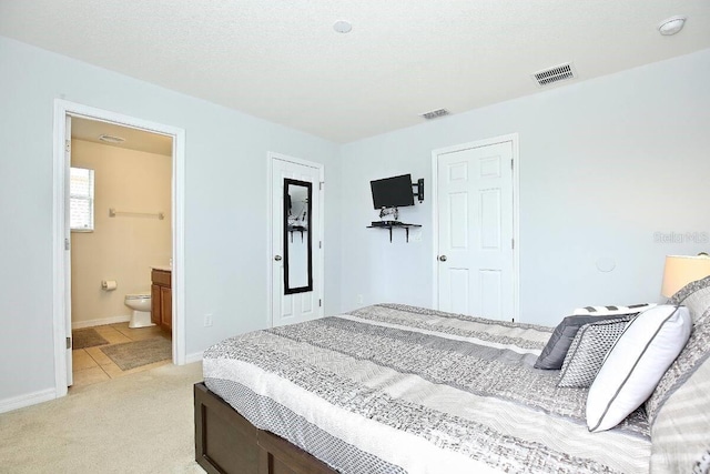 bedroom featuring light colored carpet, baseboards, and ensuite bathroom
