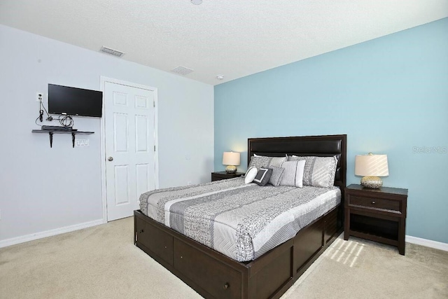 bedroom featuring light colored carpet, baseboards, and a textured ceiling
