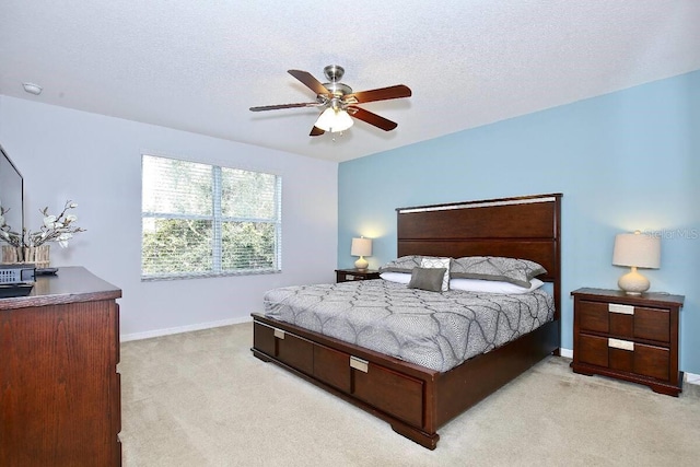 bedroom with light colored carpet, baseboards, a ceiling fan, and a textured ceiling