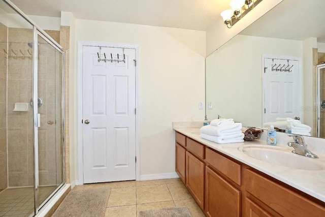 bathroom featuring a stall shower, double vanity, tile patterned floors, and baseboards