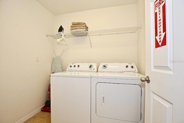 laundry area featuring washer and clothes dryer, baseboards, and light tile patterned flooring