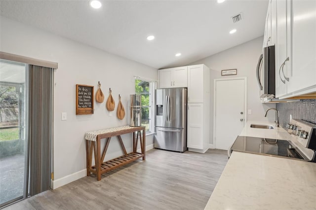 620 Fruitwood Ave, Winter Springs, FL 32708 - kitchen featuring appliances with stainless steel finishes, a sink, light wood-style flooring, white cabinets, and lofted ceiling