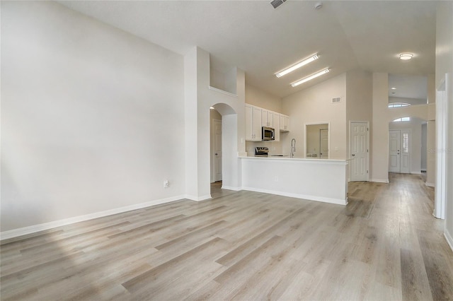19540 Glen Elm Way, Orlando, FL 32833 - unfurnished living room with arched walkways, a sink, high vaulted ceiling, light wood-type flooring, and baseboards