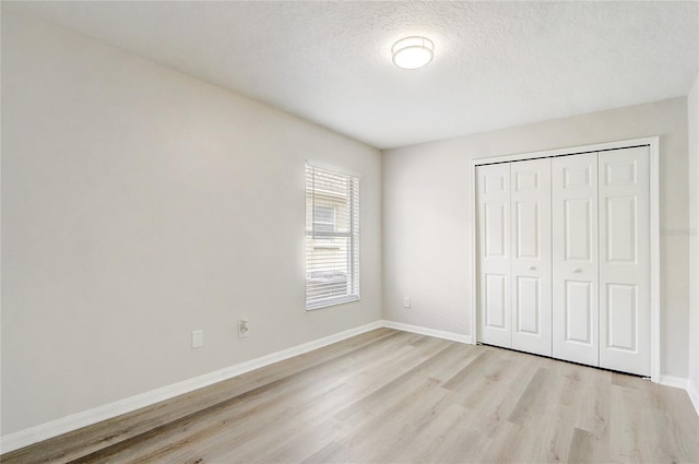 19540 Glen Elm Way, Orlando, FL 32833 - unfurnished bedroom with light wood-style flooring, a closet, baseboards, and a textured ceiling