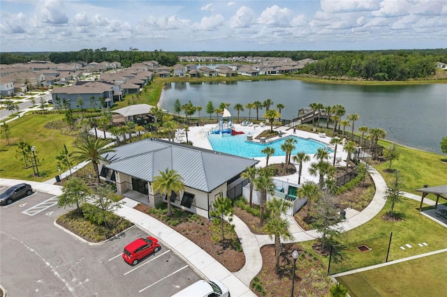 aerial perspective of suburban area featuring a pool and a large body of water