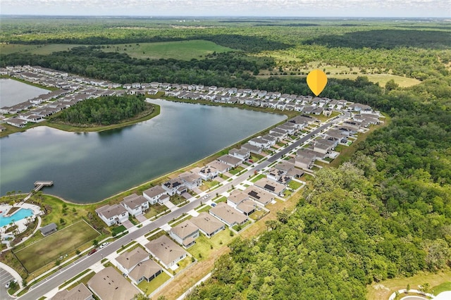 aerial perspective of suburban area featuring a forest and a large body of water