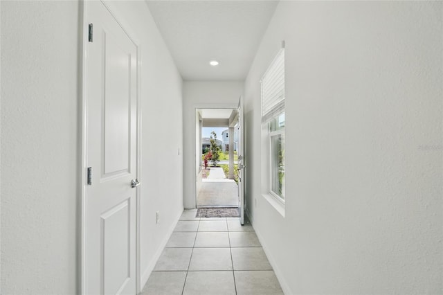 hall featuring light tile patterned floors and baseboards