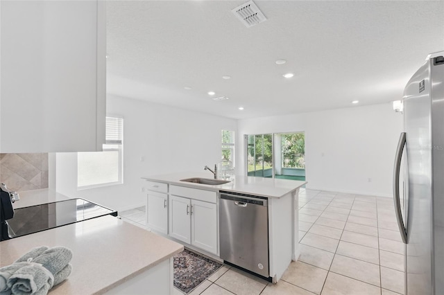 kitchen featuring appliances with stainless steel finishes, a sink, light countertops, light tile patterned floors, and white cabinets