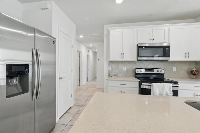 kitchen with appliances with stainless steel finishes, light tile patterned flooring, white cabinetry, tasteful backsplash, and recessed lighting