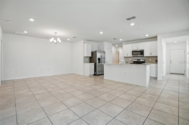 kitchen with stainless steel appliances, a chandelier, open floor plan, tasteful backsplash, and light countertops