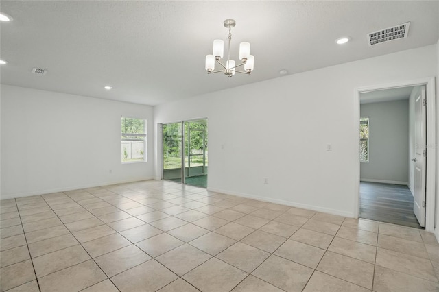 spare room featuring plenty of natural light, a chandelier, light tile patterned flooring, recessed lighting, and baseboards