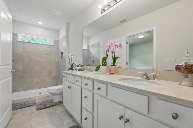 bathroom with a walk in shower, double vanity, tile patterned flooring, and toilet