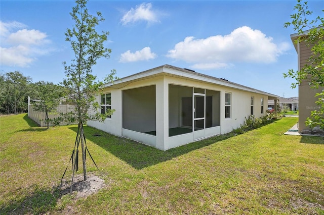 view of side of property featuring a sunroom, a yard, and stucco siding