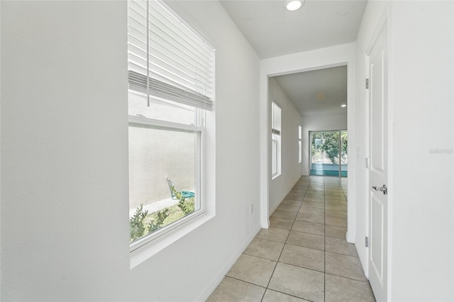 hall with plenty of natural light, light tile patterned floors, and baseboards