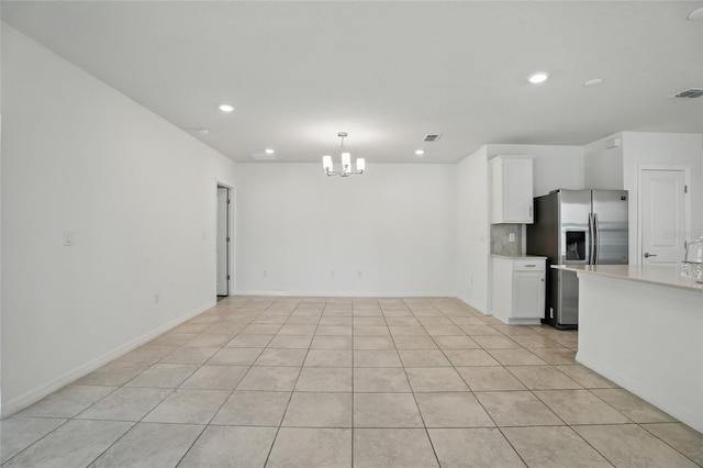 kitchen featuring stainless steel fridge, light countertops, a chandelier, white cabinets, and recessed lighting