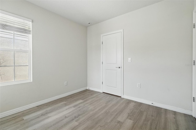 unfurnished room featuring light wood finished floors and baseboards