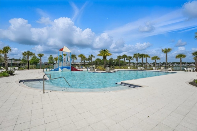 community pool featuring a water slide, a patio area, and fence