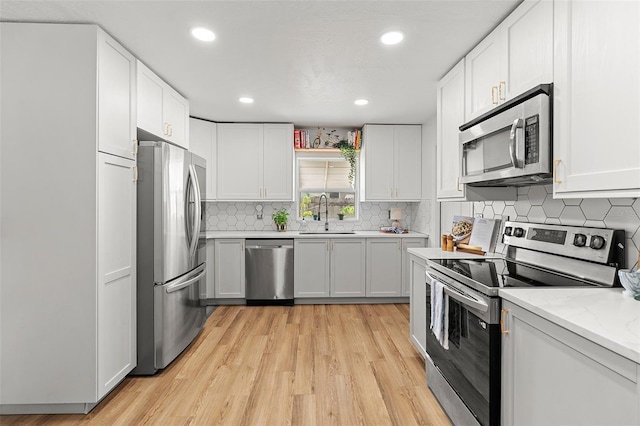 3520 Balsam Dr, Winter Park, FL 32792 - kitchen with stainless steel appliances, a sink, light wood-style flooring, recessed lighting, and white cabinetry