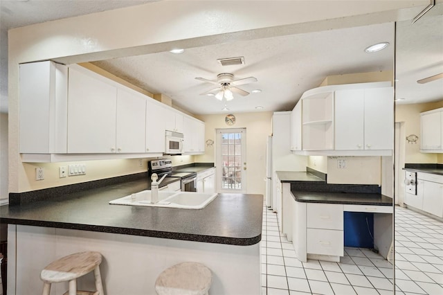 1301 Lucaya Ave, Venice, FL 34285 - kitchen with a ceiling fan, white appliances, open shelves, dark countertops, and a peninsula