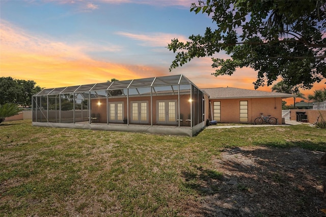 1301 Lucaya Ave, Venice, FL 34285 - back of house at dusk featuring french doors, a lawn, a patio area, and glass enclosure