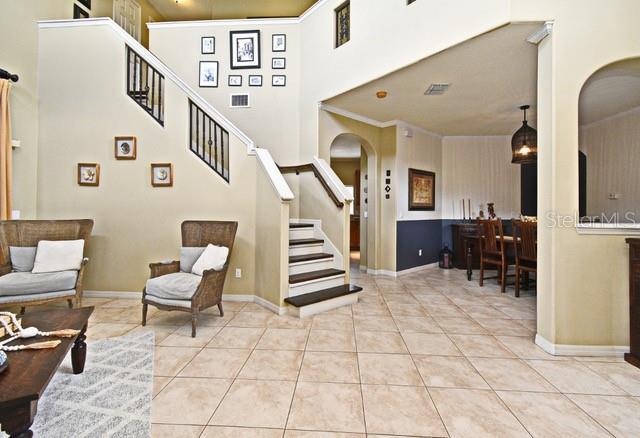 tiled foyer featuring arched walkways, stairway, a high ceiling, and baseboards