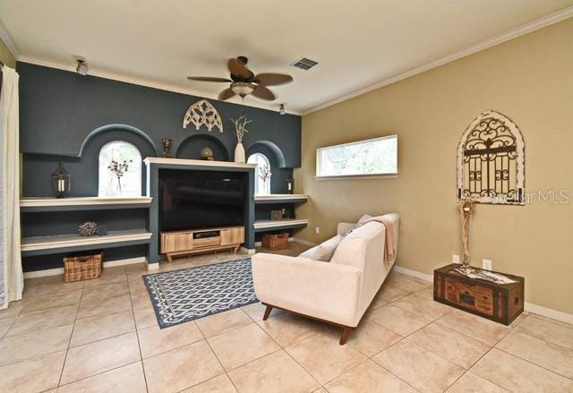 living room featuring a ceiling fan, crown molding, tile patterned floors, and baseboards