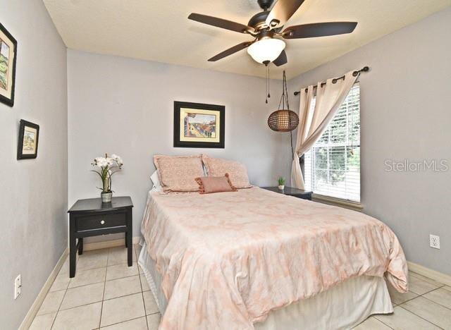 tiled bedroom featuring baseboards and a ceiling fan
