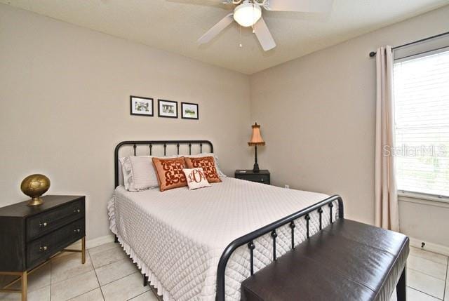 tiled bedroom with baseboards and a ceiling fan
