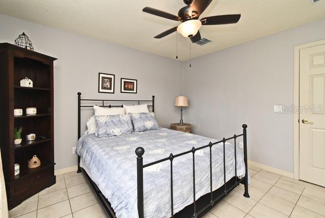 bedroom with light tile patterned flooring, baseboards, and a ceiling fan
