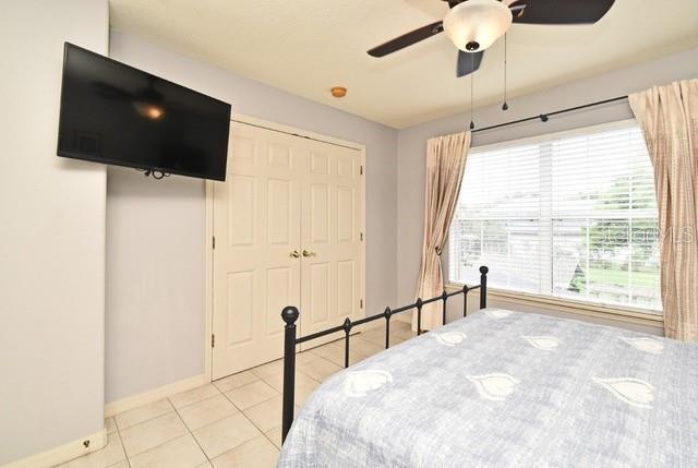 bedroom featuring light tile patterned floors, baseboards, a ceiling fan, and a closet