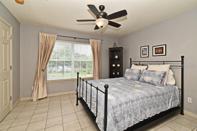 bedroom featuring baseboards, light tile patterned floors, and ceiling fan