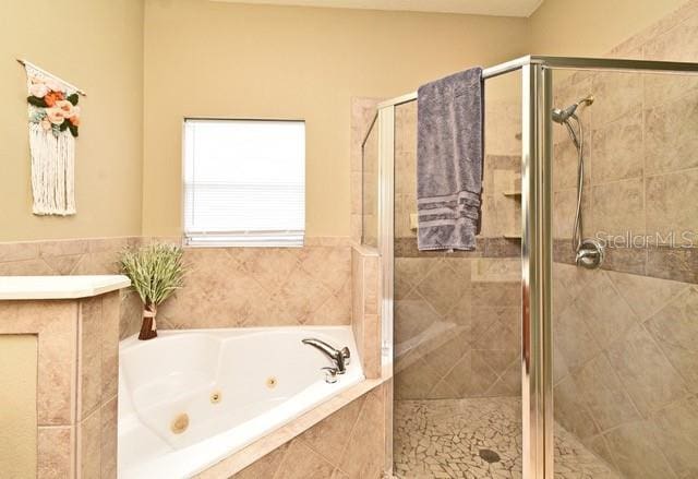 bathroom with a jetted tub and a shower stall