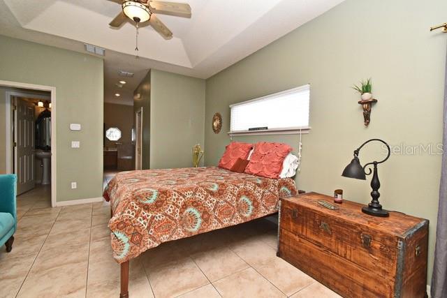 bedroom with a raised ceiling, tile patterned floors, baseboards, and ceiling fan